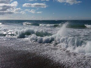 Een strand met golven die op het strand breken onder een heldere lucht.