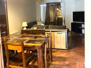 Un espace de vie compact comprenant une table à manger, des chaises, un canapé, un téléviseur et un meuble.