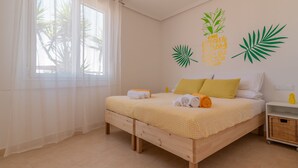A bedroom with a bed, a nightstand, a window with sheer curtains, and wall decorations. - Your oasis of peace in Corralejo, views of the ocean and volcanoes. Top pool! (Corralejo)