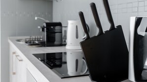 A modern kitchen with a black induction cooktop, a white coffee maker, and a black knife block. - Your oasis of peace in Corralejo, views of the ocean and volcanoes. Top pool! (Corralejo)