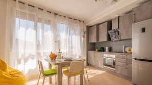 A modern kitchen with a dining area, featuring a wooden table, chairs, and a bright yellow bean bag. - Your oasis of peace in Corralejo, views of the ocean and volcanoes. Top pool! (Corralejo)