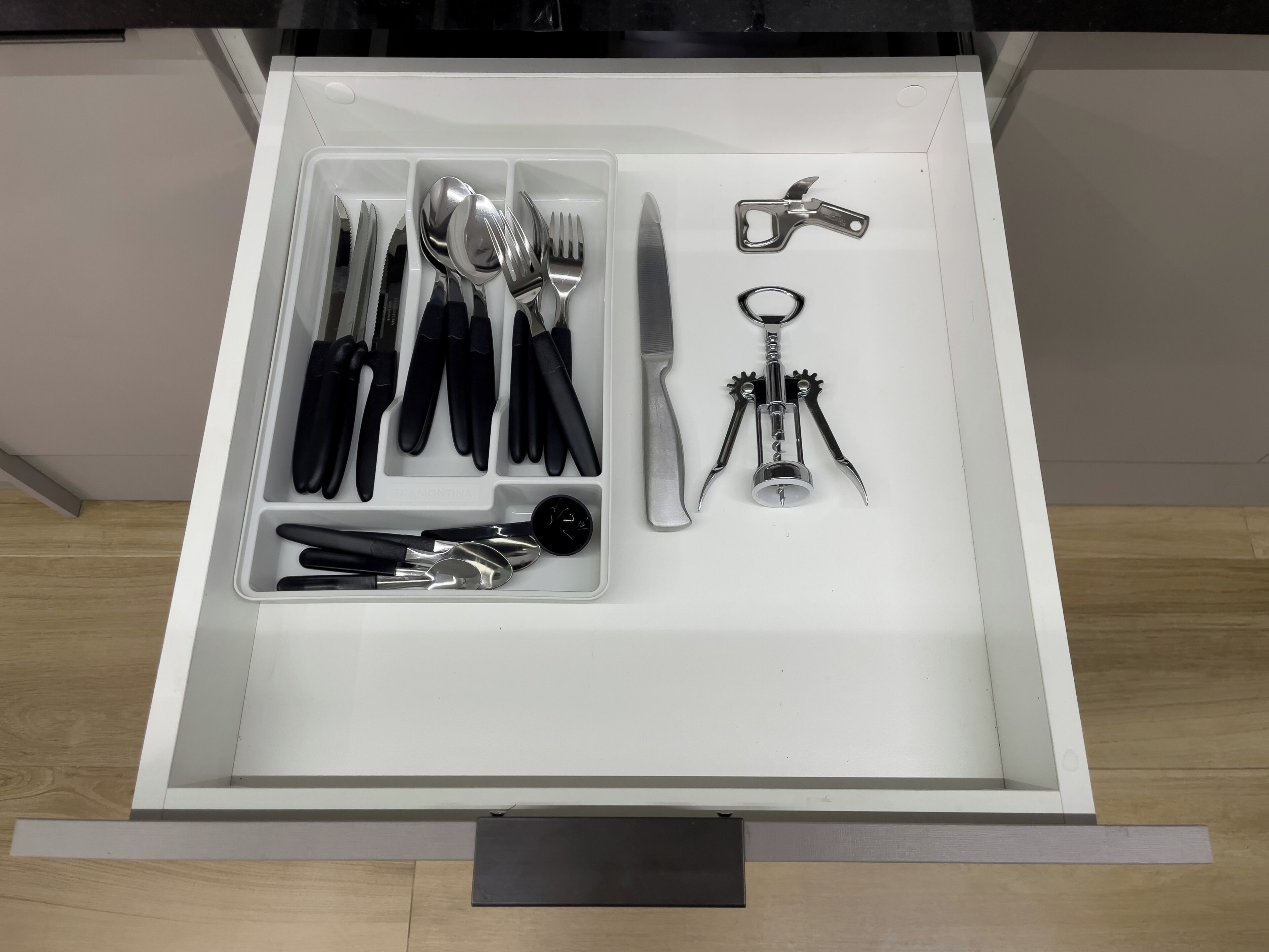 Un tiroir contenant divers ustensiles et outils, notamment des couteaux, des cuillères et un tire-bouchon.