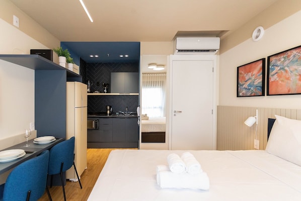 Una habitación de hotel moderna con cama, comedor y kitchenette.
