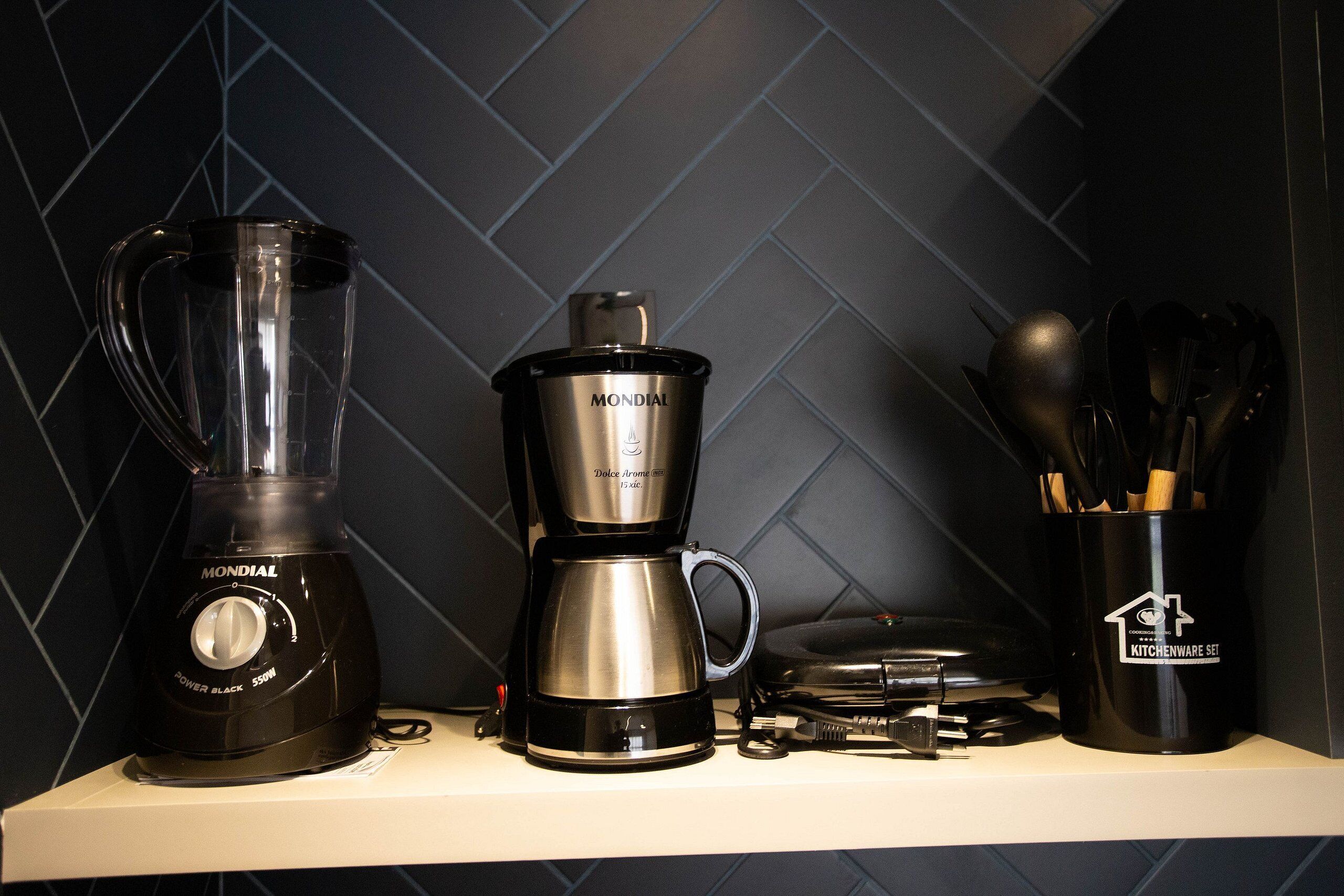 Una encimera de cocina con una licuadora, una cafetera y un recipiente para utensilios.