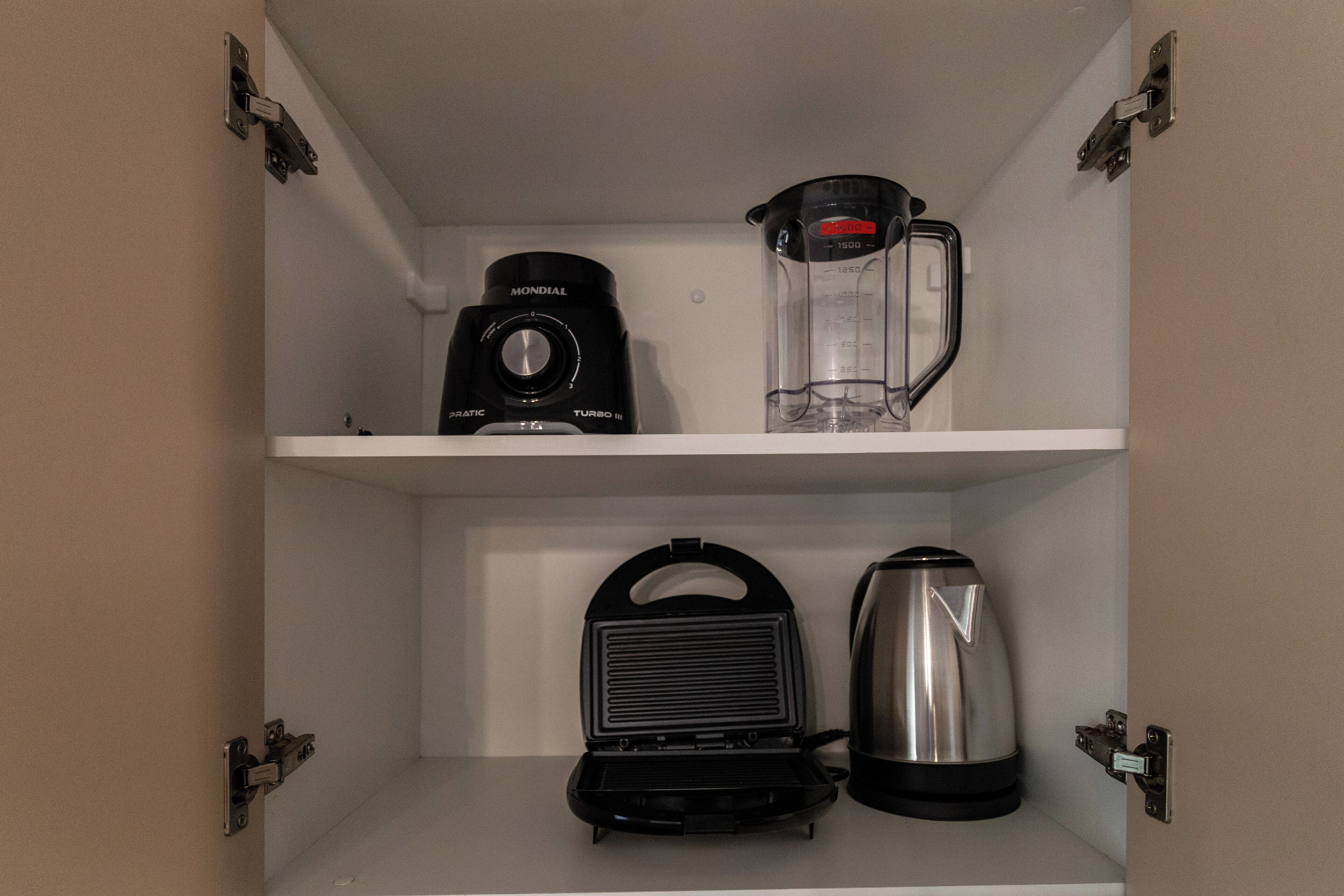 Una cocina con cafetera, licuadora y hervidor en la encimera.