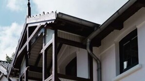 Un bâtiment doté d’une grande baie vitrée et d’un balcon avec des poutres en bois foncé.