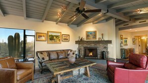A spacious living room with a fireplace, leather furniture, and ceiling fans. - Private Foothills Villa + Panoramic Views + Heated Pool/Spa (Tucson)