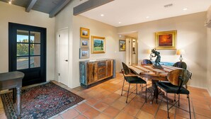 A dining area with a wooden table and chairs, a decorative cabinet, and framed pictures on the wall. - Private Foothills Villa + Panoramic Views + Heated Pool/Spa (Tucson)