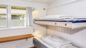Ein Schlafsaalzimmer mit Etagenbetten, einem Fenster mit Vorhängen und einem Nachttisch.