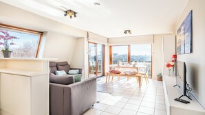 A modern apartment with a living area, dining space, and a balcony with a city view. - Apartment in Oostduinkerke Near the Beach (Koksijde)