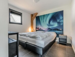 Une chambre à coucher avec un lit, une table de chevet, un bureau et une grande fenêtre.