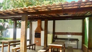 An outdoor patio with a brick oven, wooden tables, and benches. - Apartamento Charmoso a 100 m da Praia Grande Arraial do Cabo (Arraial do Cabo)