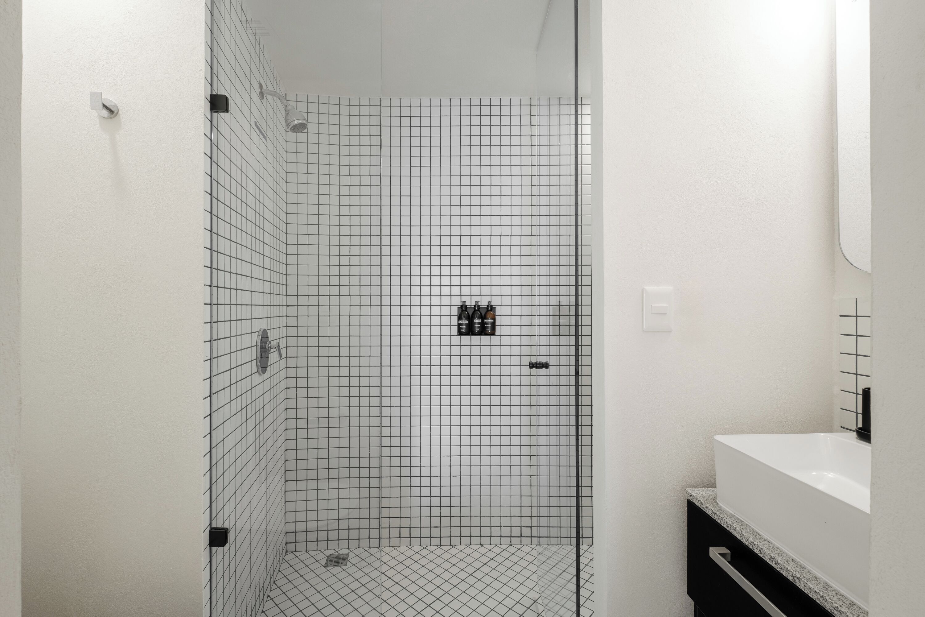 Un baño moderno con cabina de ducha de diseño de cuadrícula, un lavamanos blanco y un espejo.