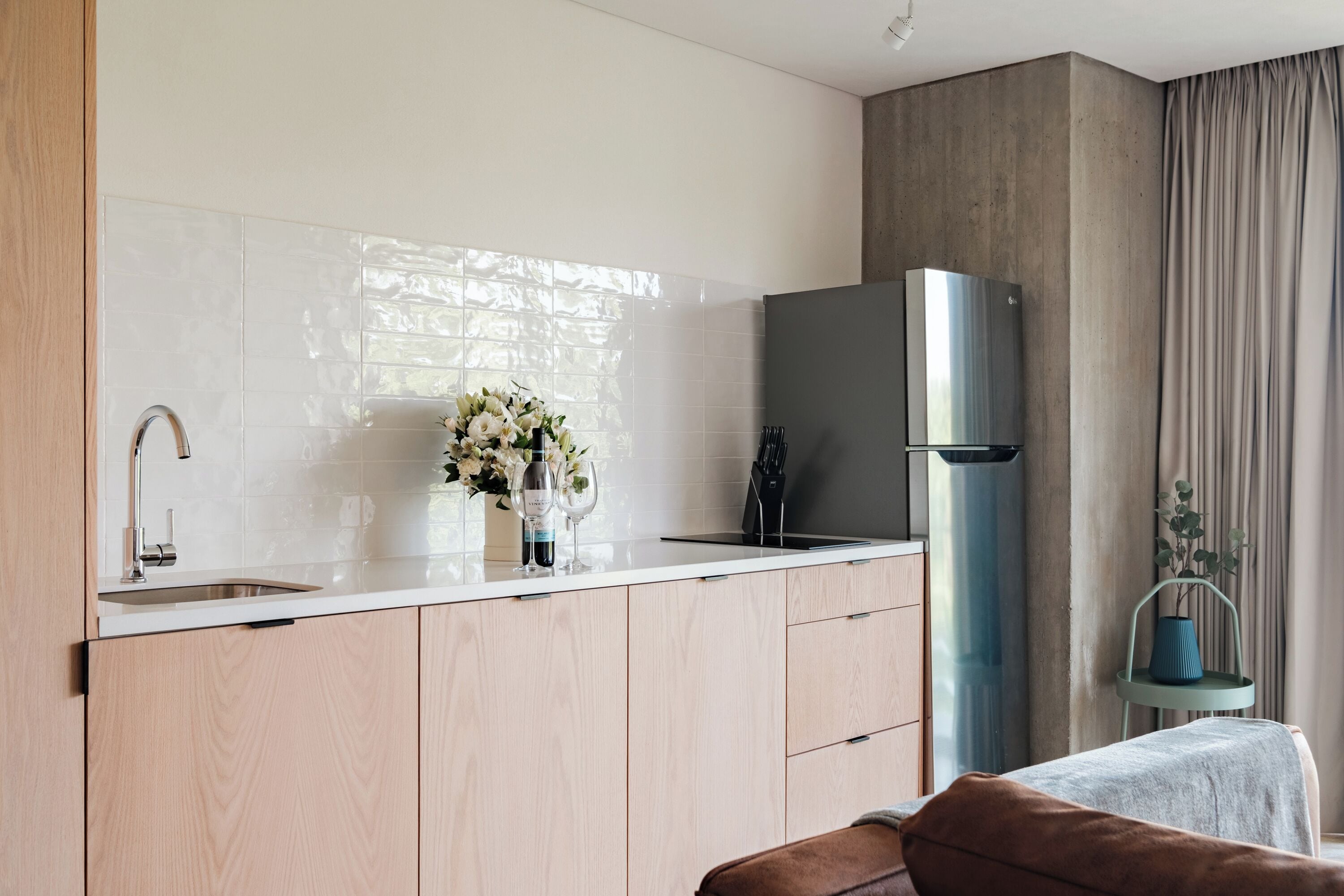 Une cuisine moderne avec un réfrigérateur en acier inoxydable, un évier et un vase de fleurs posé sur le plan de travail.