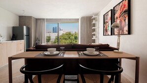 Un área de comedor moderna con vistas al horizonte de la ciudad, un sofá y una mesa dispuesta para dos personas.