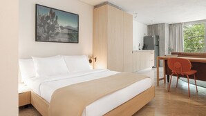 Una habitación de hotel moderna con cama, escritorio y kitchenette.