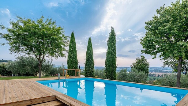 Ein rechteckiger Swimmingpool mit einer Holzterrasse und einem kleinen Tisch.