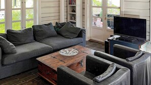 A living room with a grey sofa, a wooden coffee table, a leather armchair, and a television.