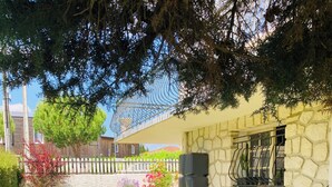 A round wooden table with four chairs, a grill, and a stone wall with a window. - Ground floor flat with garden - 3*** furnished holiday home- all comforts - wifi (Saintes)