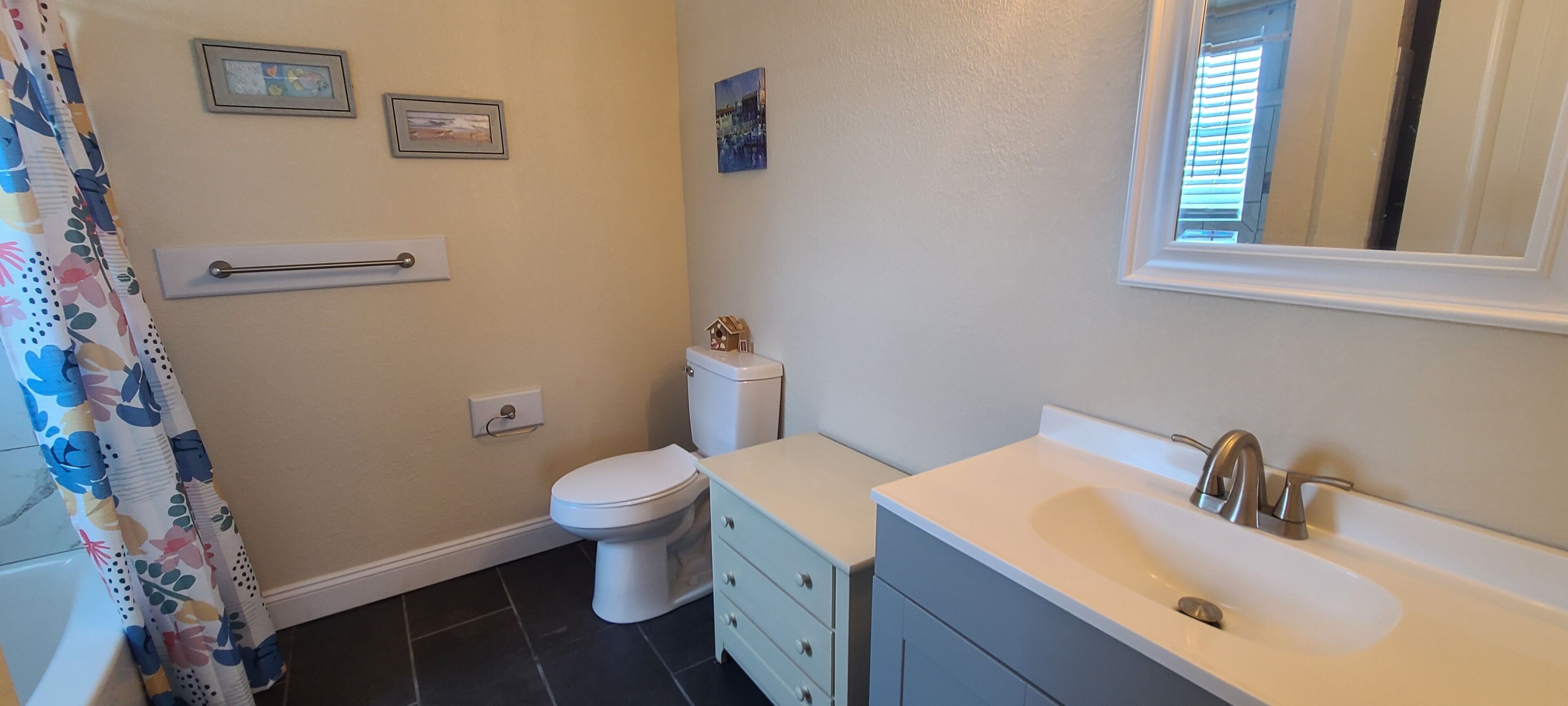 Een badkamer met toilet, wastafel, spiegel en douchegordijn.