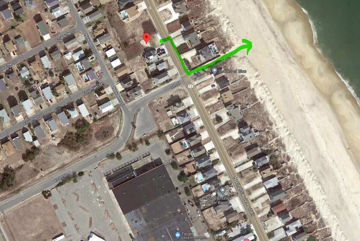 Luchtbeeld van een kustbewoonde wijk met straten genaamd Charlotte St, Durham St en 5th St. Een groene pijl geeft een route aan van het centrum naar het strand, waar 'Shades of Blue' gemarkeerd staat.