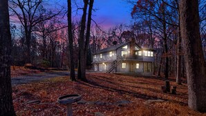 Une maison à deux étages avec un balcon, entourée d’arbres et dotée d’une allée.