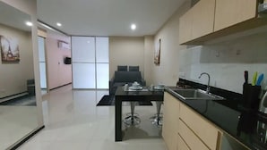 Cozinha moderna com área de jantar, destacando uma mesa de jantar preta, eletrodomésticos de aço inoxidável e um design minimalista.