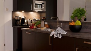 A modern kitchen with dark cabinetry, a stainless steel sink, a microwave, and a coffee maker. - Spacious Retreat, Vlagtwedde (Vlagtwedde)