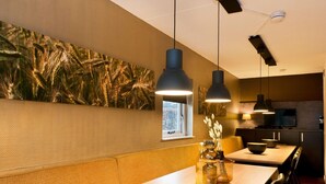 A modern dining area with a long wooden table, black pendant lighting, and a large wall mural. - Spacious Retreat, Vlagtwedde (Vlagtwedde)