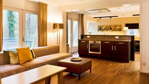 A modern living room with a sofa, a coffee table, and a kitchen area with a stove and cabinets. - Spacious Retreat, Vlagtwedde (Vlagtwedde)