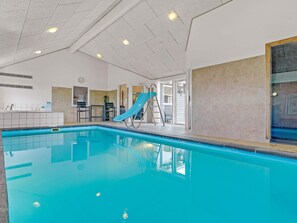 An indoor swimming pool with a slide, a ladder, and a view of the outside. - Luxury Retreat by Beach - By Traum Ferienwohnungen (Idestrup)