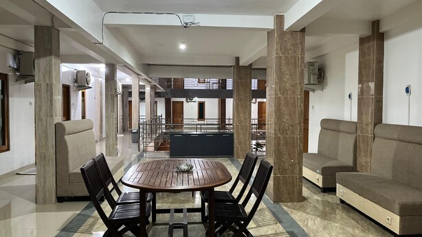 A spacious indoor area with a round wooden table surrounded by chairs, a sofa, and a TV mounted on the wall.