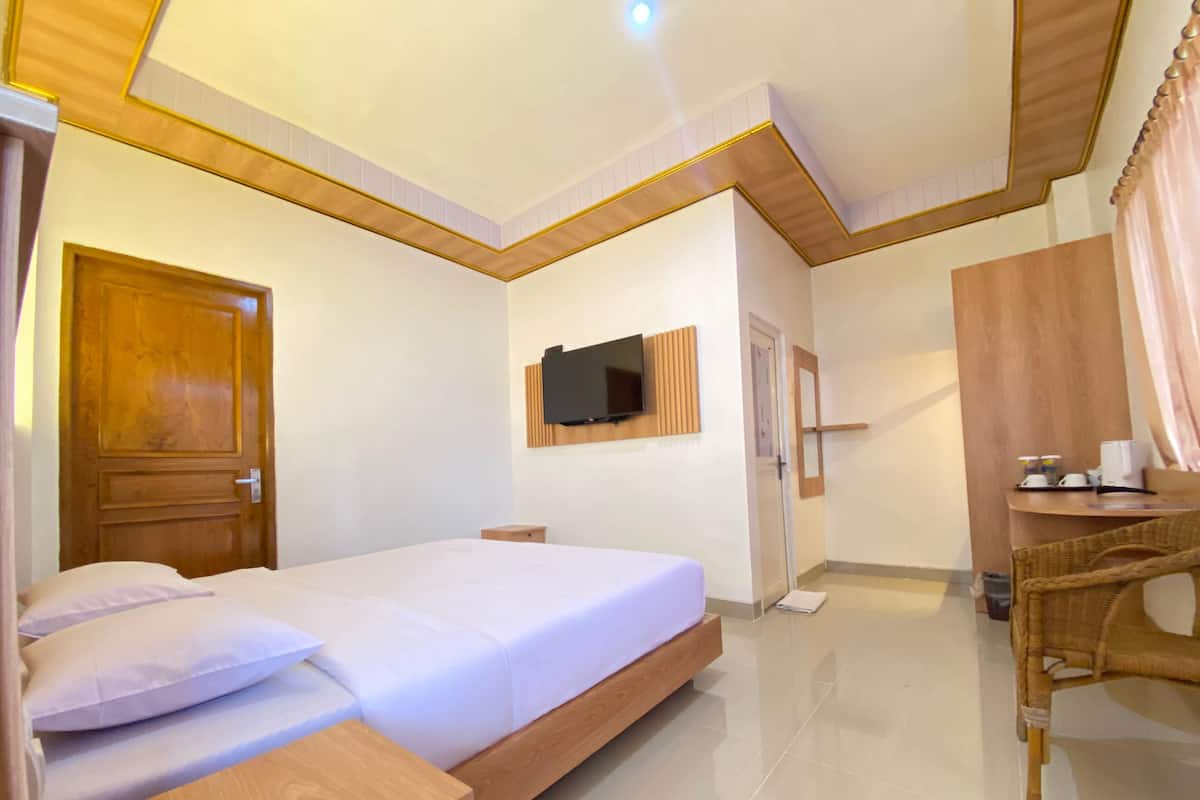 Une chambre d’hôtel avec un lit, un téléviseur fixé au mur, un bureau en bois et une chaise.