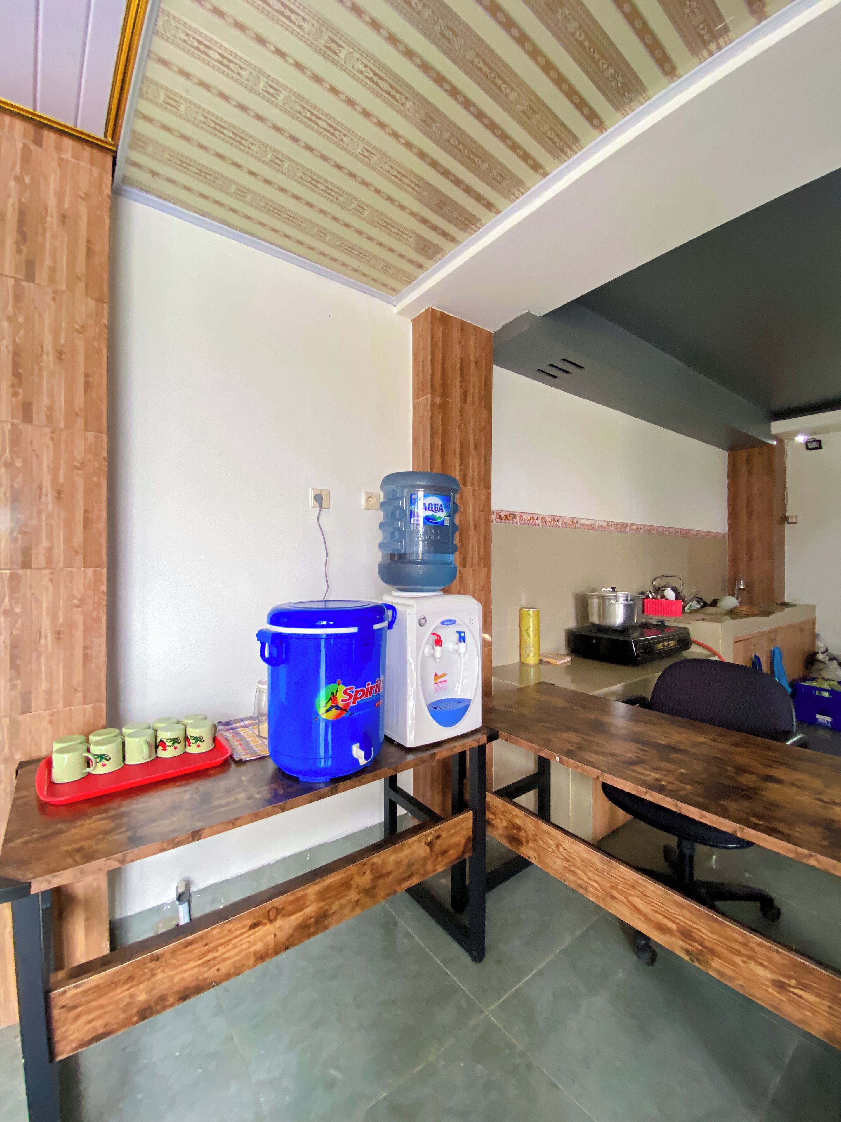 A kitchen area with a water dispenser, a large water jug, and a red tray with mugs.