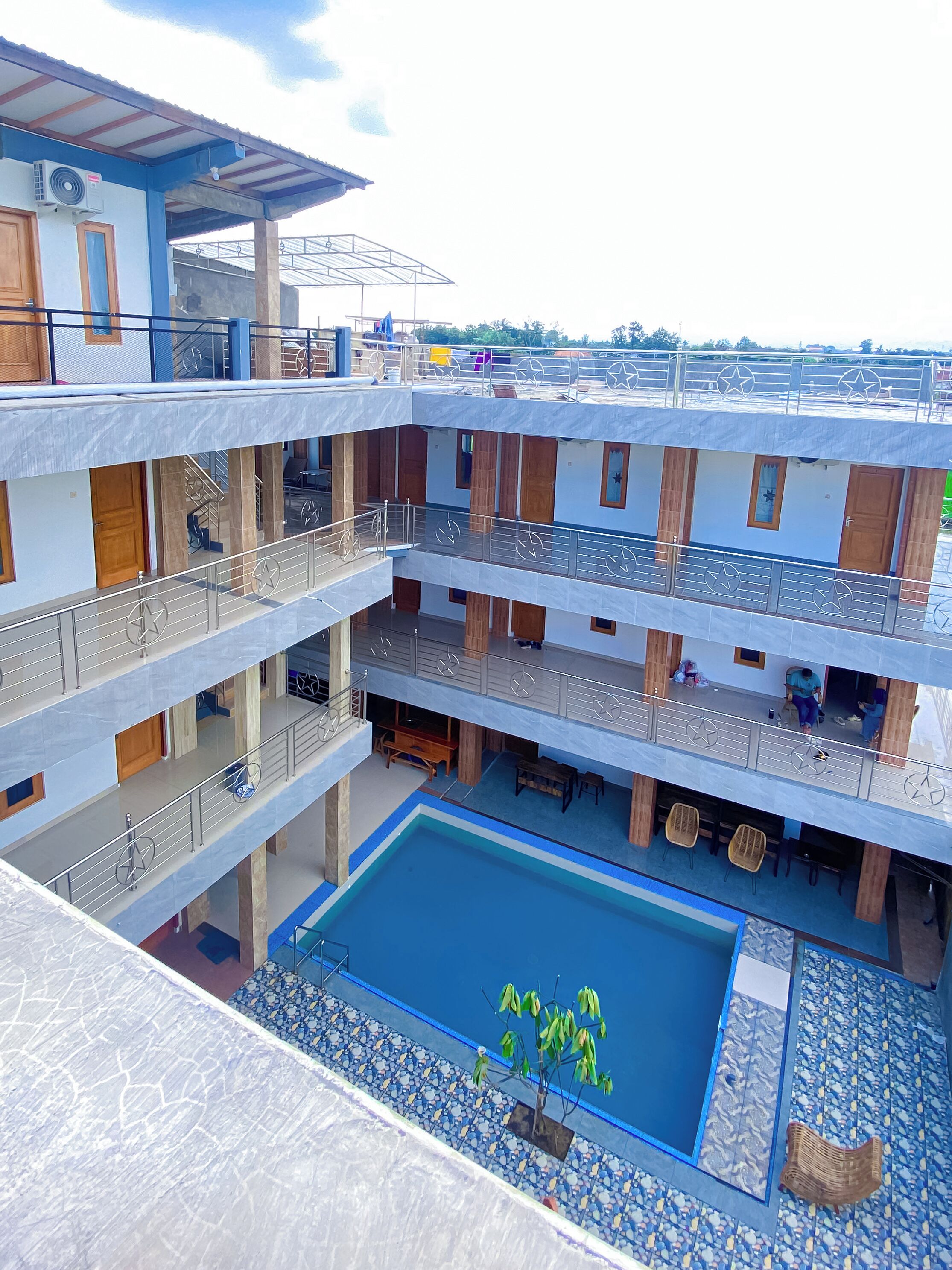 A multi-story building with a central courtyard pool, balconies, and a covered area with seating.