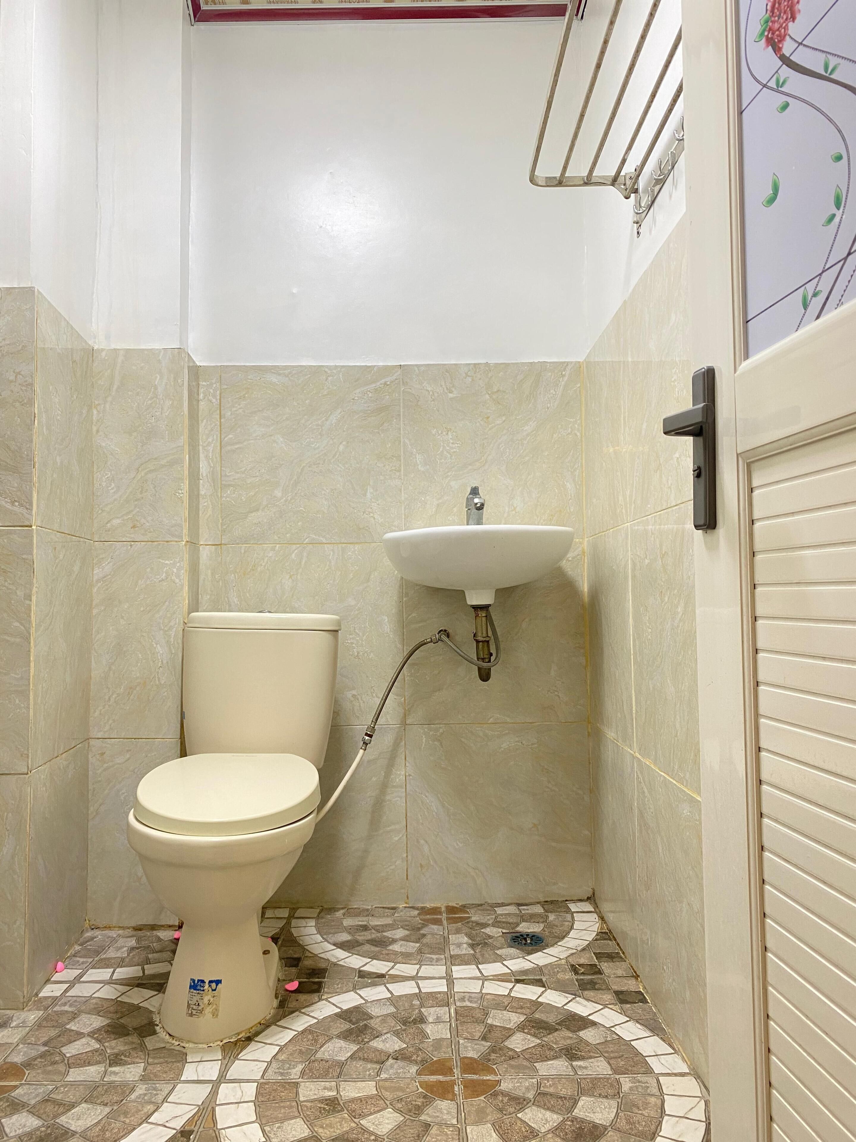 Ein kleines Badezimmer mit Toilette, Waschbecken und Fliesenboden.