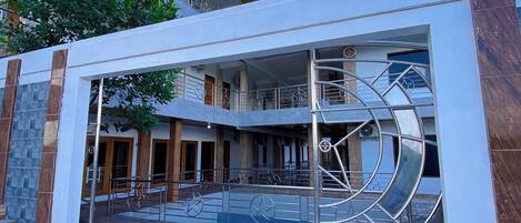 A modern building with a central courtyard, featuring a metal gate with star designs, a staircase, and a balcony with railings.