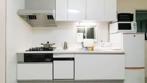 A kitchen with white cabinets, a microwave, a stove, and a dishwasher. - Villa de Class (Osaka)