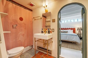 A bathroom with a toilet, sink, and shower curtain featuring a desert landscape design. - Stunning Artful Adobe - Super Walkable Location (Santa Fe)