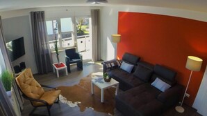 A modern living room with a sofa, a chair, a coffee table, and a TV. - Holiday Apartment Erlebnisrhoen (Ehrenberg)