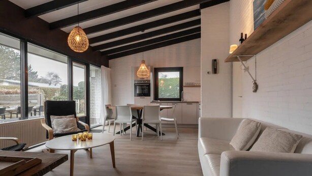Ein modernes Wohnzimmer mit großem Fenster, Essbereich und Küche.