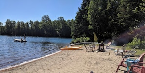 A lakeside beach with a kayak, chairs, and a small boat. - BIG Comfy Lakefront cottage, Clear Lake by Huntsville, north Muskoka! (Emsdale)