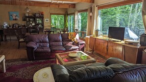Una sala de estar acogedora con un sofá de cuero, una mesa de centro y un televisor sobre un mueble de madera.