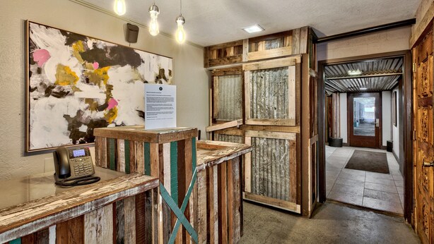 A reception desk with a telephone, a framed abstract painting, and a wooden wall panel. - Holiday Inn Express South Lake Tahoe by IHG (South Lake Tahoe)