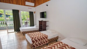 A hotel room with two beds, a TV, and a balcony with a view of greenery. - HOTEL SIERRA ARENAL - QUADRUPLE ROOM  (Alajuela)