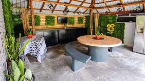 An outdoor patio with a round table, a built-in kitchen area, and a ceiling fan. - HOTEL SIERRA ARENAL - QUADRUPLE ROOM  (Alajuela)