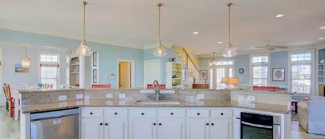 A spacious kitchen with white cabinets, a built-in oven, and pendant lighting.