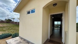 A house with a tiled entrance, a small window, and a view of the surrounding landscape. - Cabañas Colibri (Valle de Guadalupe)