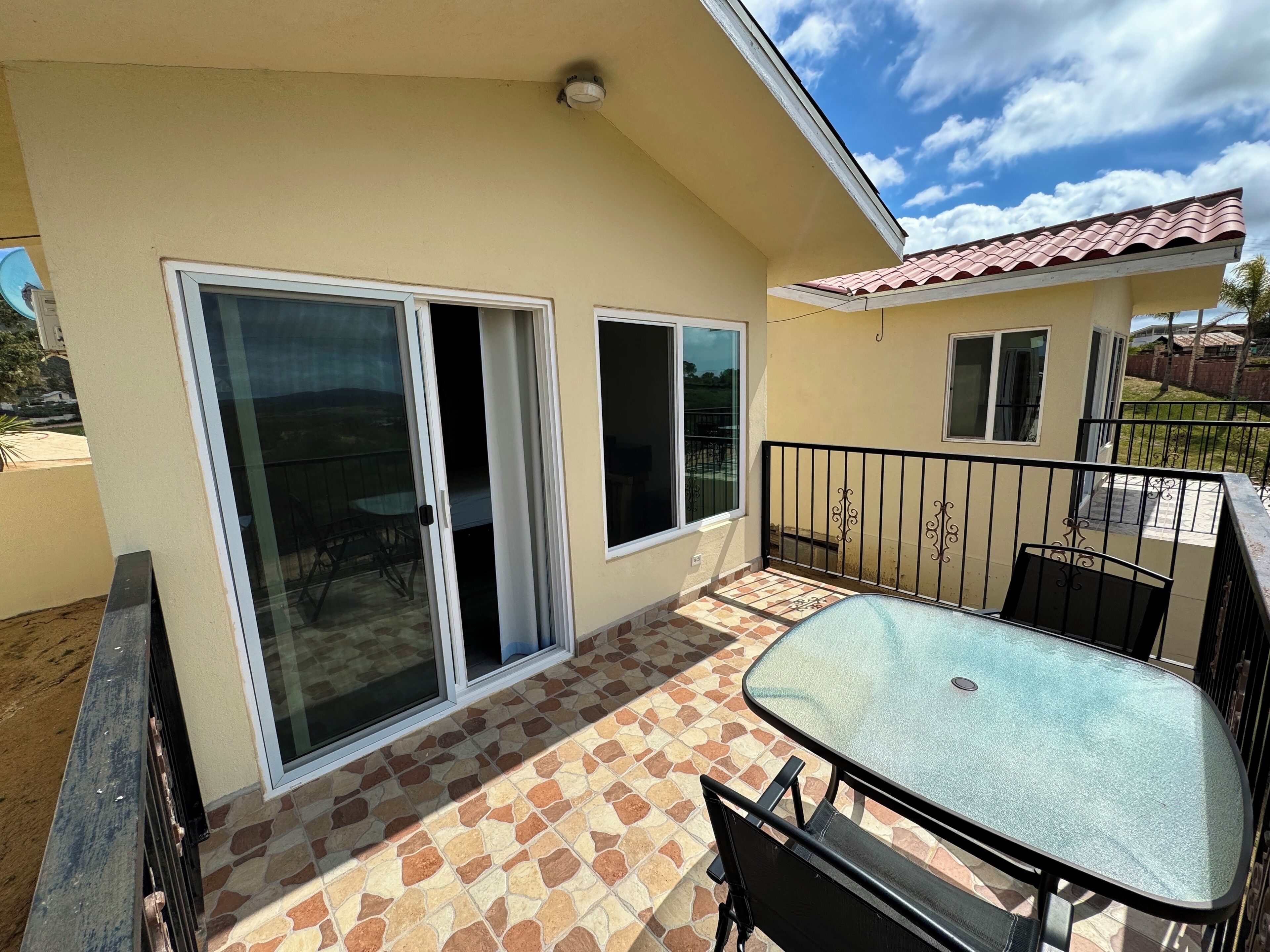 Un balcon avec une porte-fenêtre, une table et des chaises.