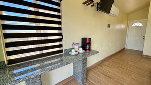 A kitchen with a granite countertop, a coffee maker, and a wall-mounted TV. - Cabañas Colibri (Valle de Guadalupe)